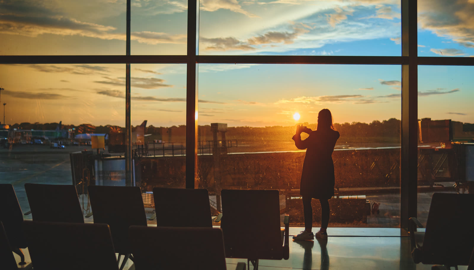 Traveler in a glass departure hall at sunset