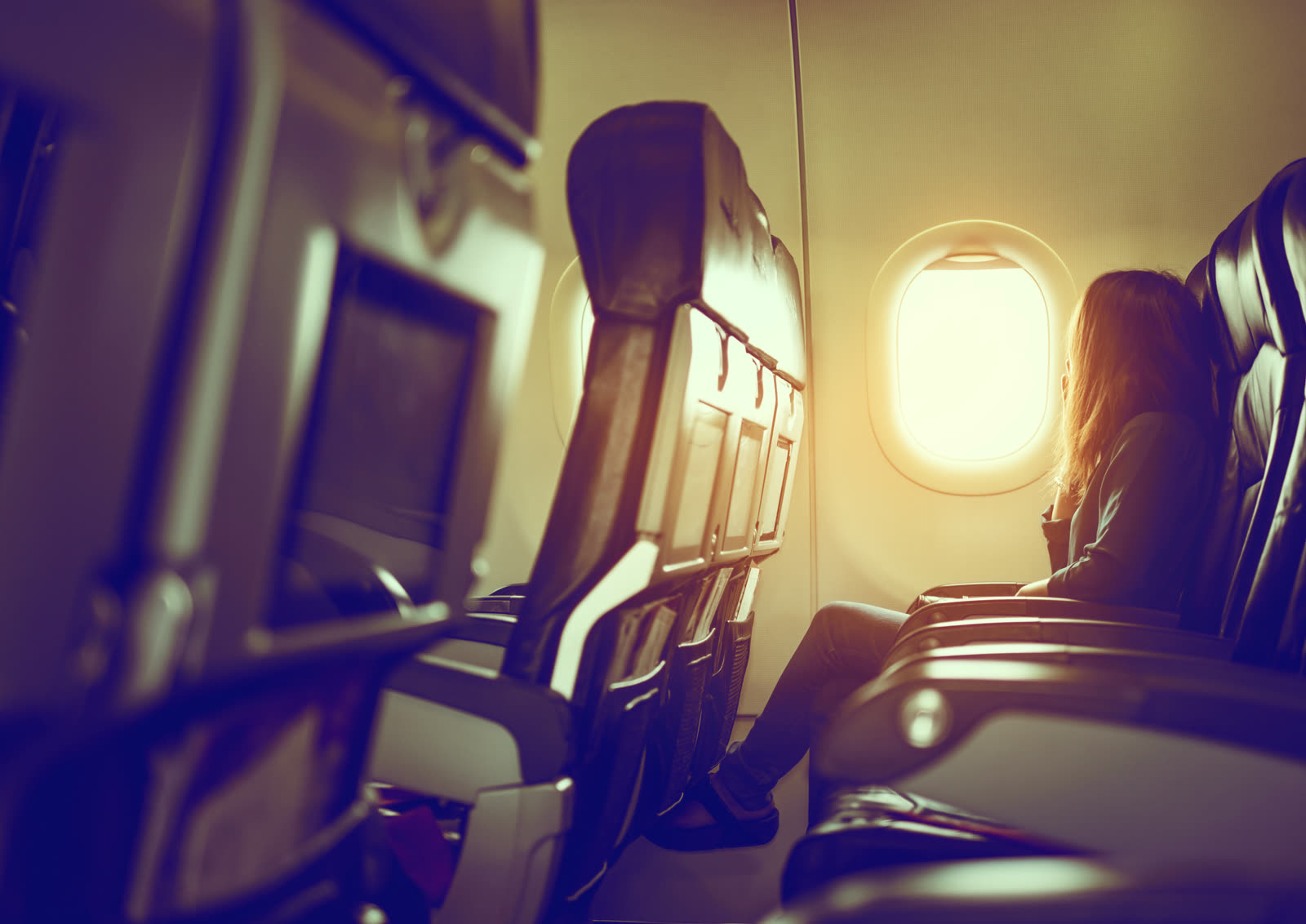 Passenger at a cabin window over a sea of clouds